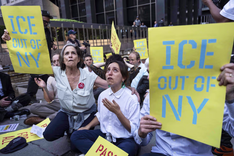 Demonstrators, holding yellow and blue signs that read "ICE Out of NY" chant during a protest against Immigration and Customs Enforcement