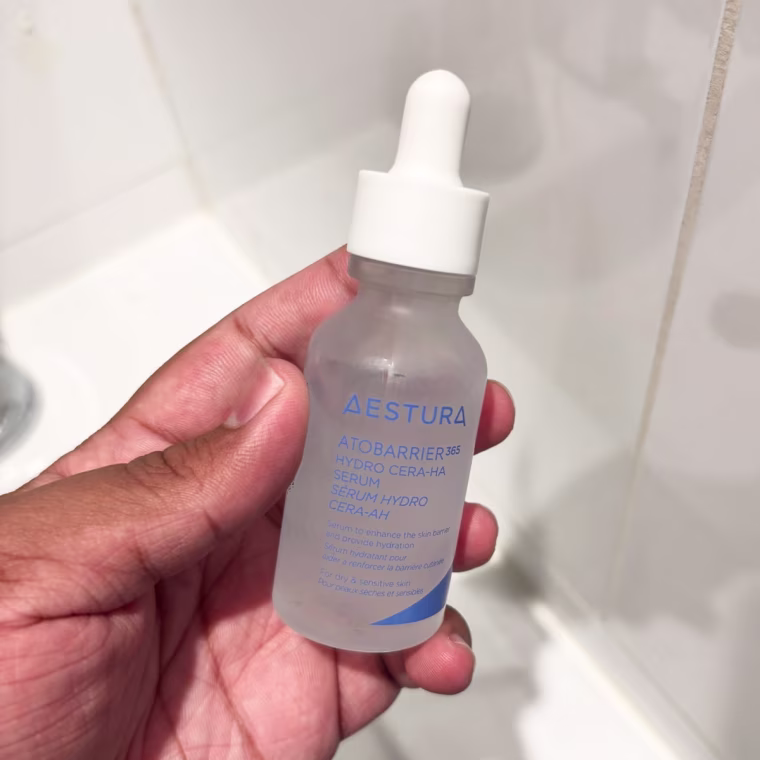 Person holding clear bottle of the Aestura Atobarrier serum.
