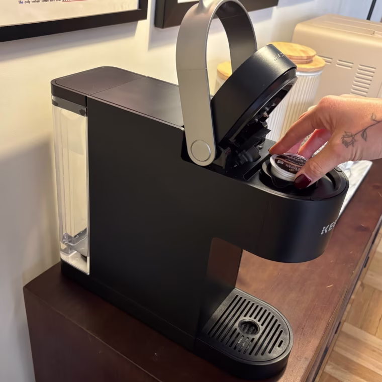 A black Keurig K-Slim Single-Serve Coffee Maker on a wood countertop.