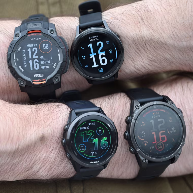 A close up of four different Garmin watches on the wrists of the writer.