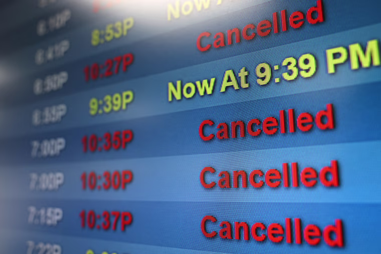 An arrivals board shows delayed and cancelled flights