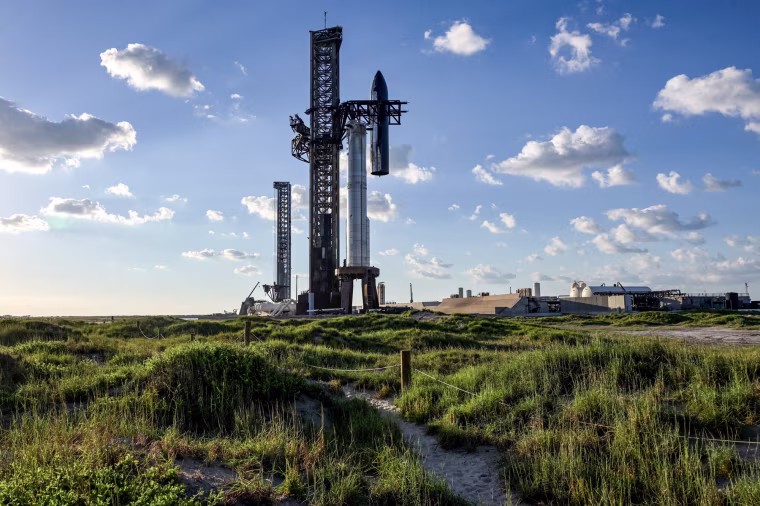 The SpaceX Starship spacecraft is hoisted along the launch tower for stacking atop the Super Heavy booster outside, seen from a distance