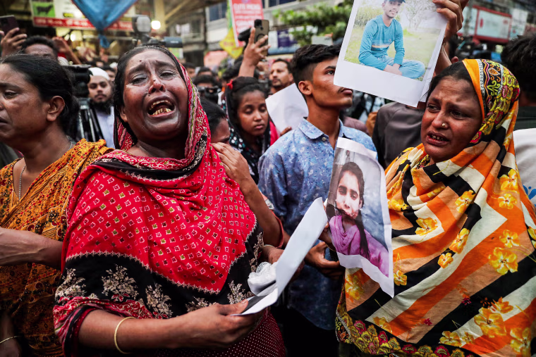 Women crying as they show photographs of fire accident victims