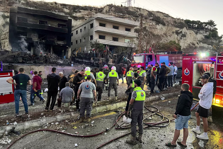 Rescuers and first-responders stand outside a damaged building following an overnight Israeli strike in Msayleh, southern Lebanon, on Oct. 11, 2025. 