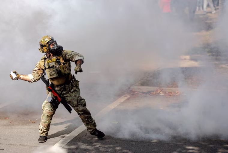 A federal agent throws a tear gas canister during clashes with community members on Chicago’s South Side on Oct. 14. 