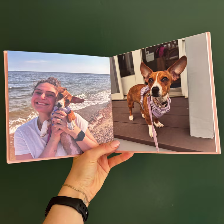 Woman holding open a photo book with pictures of her and a dog