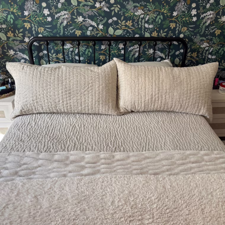 The Quince European Cotton Stitch Quilt Set in a tan color on a bed.