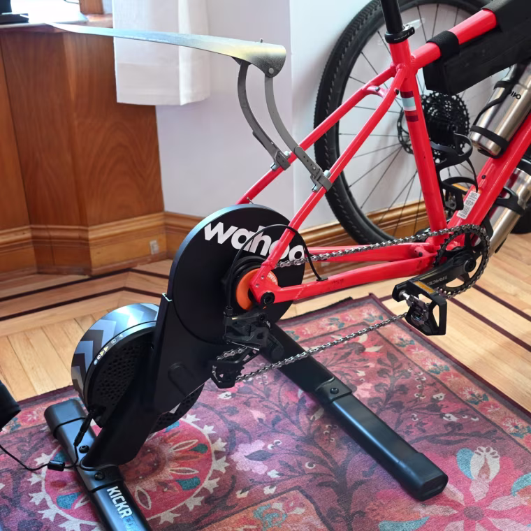 A close up of the Wahoo Kickr Core 2 bike trainer on a red bike against a floral carpet.