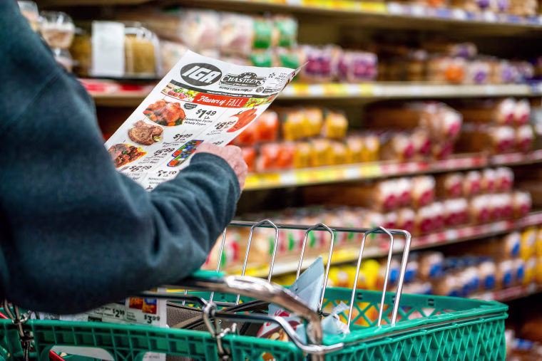A shopper looks at a sales advertisement at a grocery store.