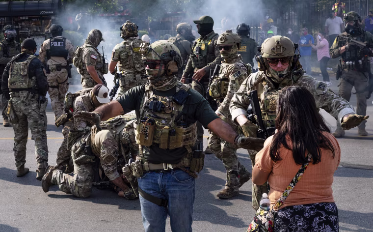 Police take two people into custody, as tear gas fills the air after it was used by federal law enforcement agents in Broadview, IL.