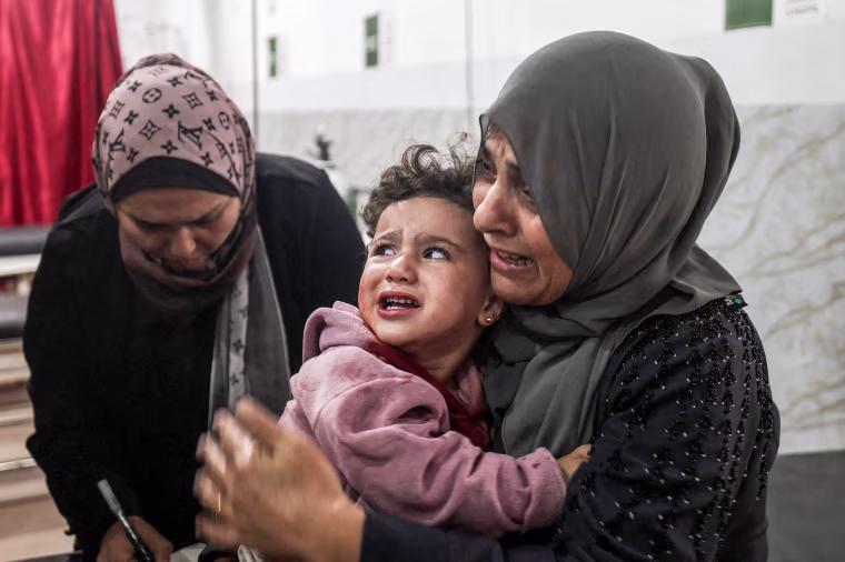 A woman holds a baby crying.