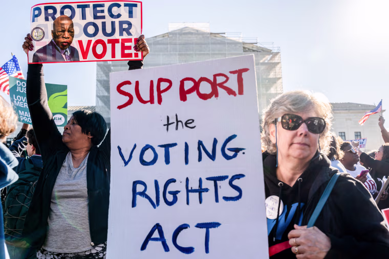 Protestors hold signs outside of the Supreme Court building, one says "Support the voting rights act" and another says "Protect our vote"