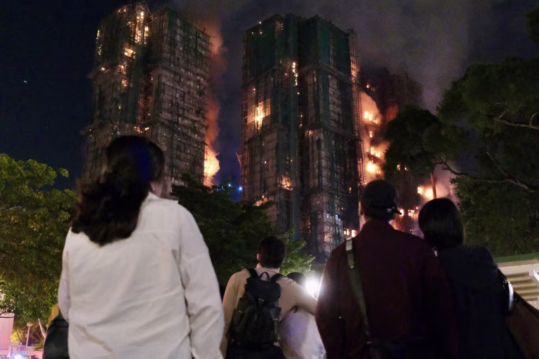 Image: People look on as thick smoke and flames rise during a major fire at the Wang Fuk Court residential estate