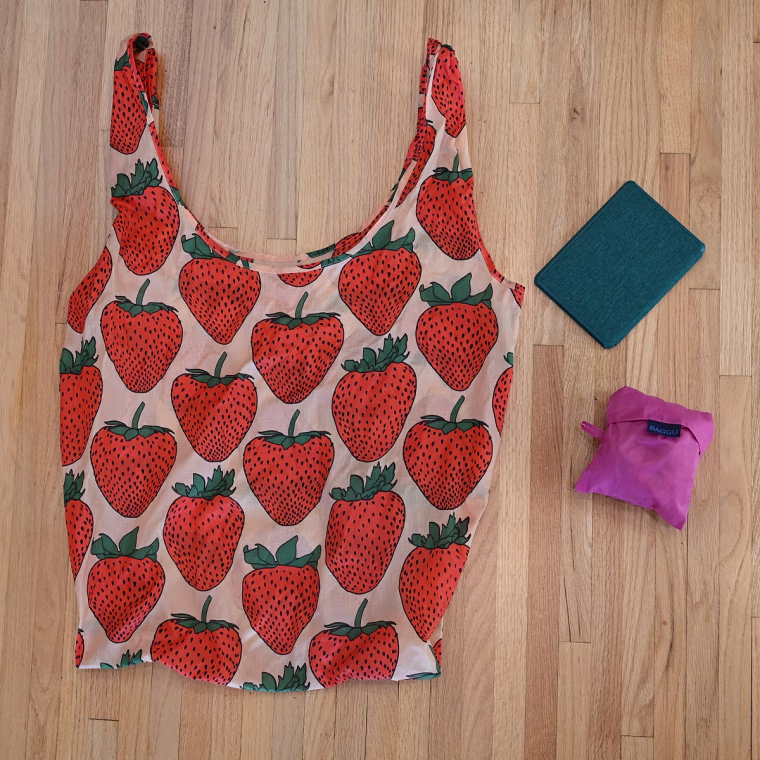 A photo of a large Baggu, folded Baggu and Kindle Paperwhite on a wooden floor.