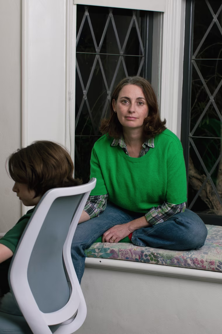 Lila sits next to her son, sitting in a computer chair.