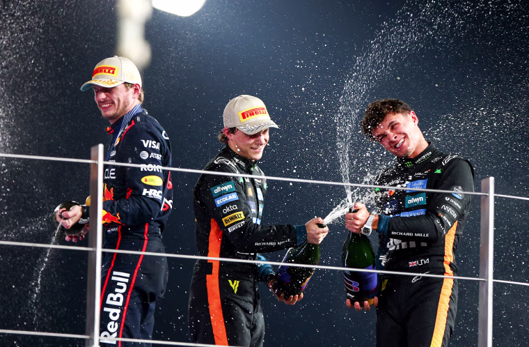 From left, Max Verstappen, Oscar Piastri, and Lando Norris pop champagne on a balcony outside