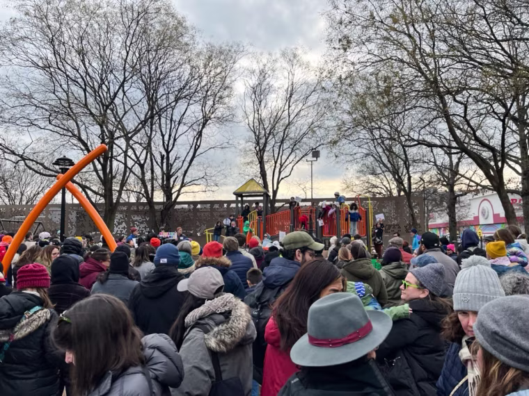 People gather outside at a playground for a protest