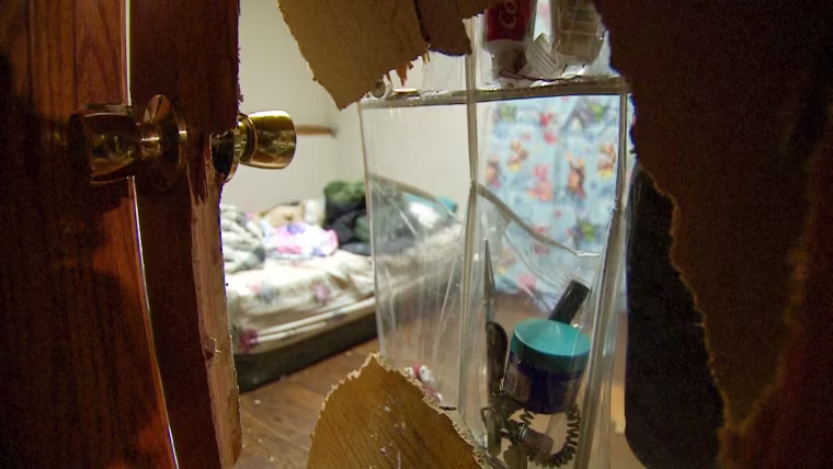A hole in a wooden door to a bedroom