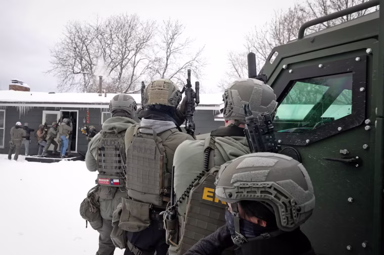 ICE agents enter a home outside St. Paul, Minn., looking for a suspect charged with criminal sexual contact on Dec. 10, 2025.