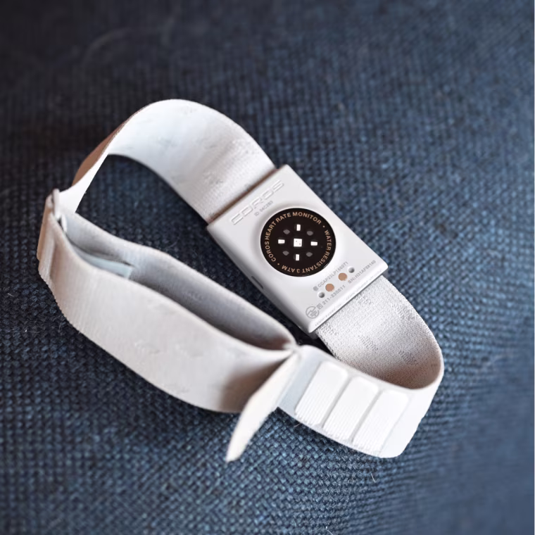 A close-up of the Coros Heart Rate Monitor resting on a blue fabric cushion.