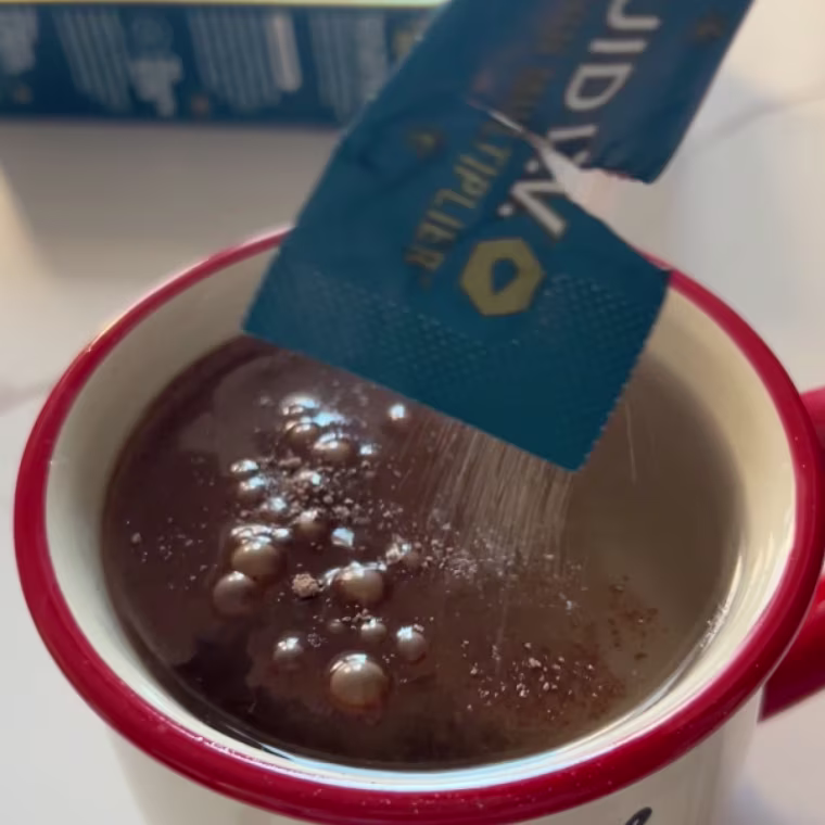 Woman pouring a Liquid IV hot chocolate packet into a mug