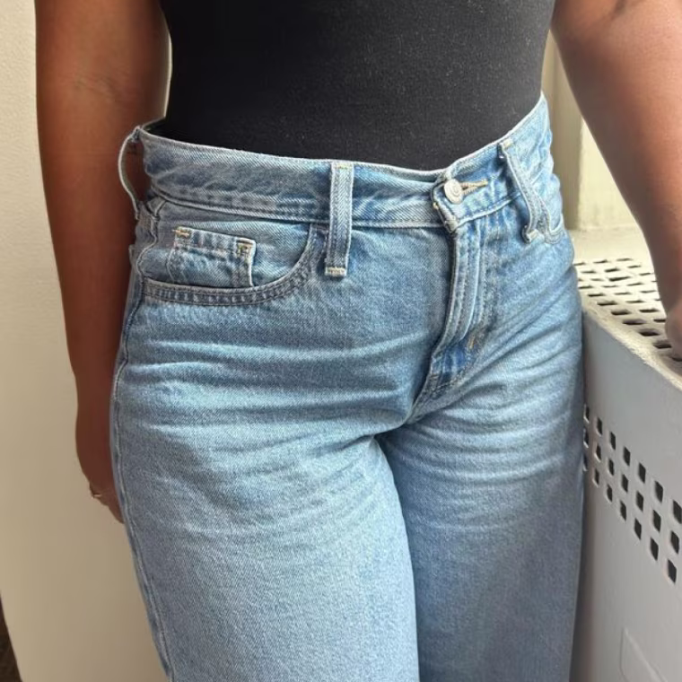 Woman wearing light wash jeans and a black top