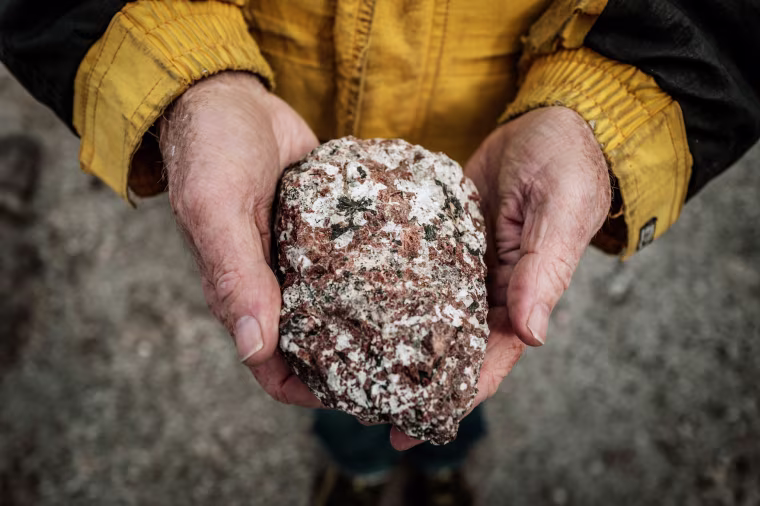 Geologist Greg Barnes, former owner of the Tanbreez rare earth minerals site, holds up a rock containing crystals at a mining site