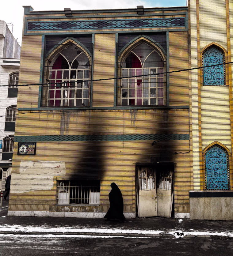 A woman passes a damaged mosque in Tehran on Wednesday.