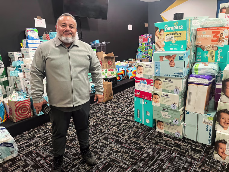 Sergio Amezcua stands next to boxes of diapers and other goods