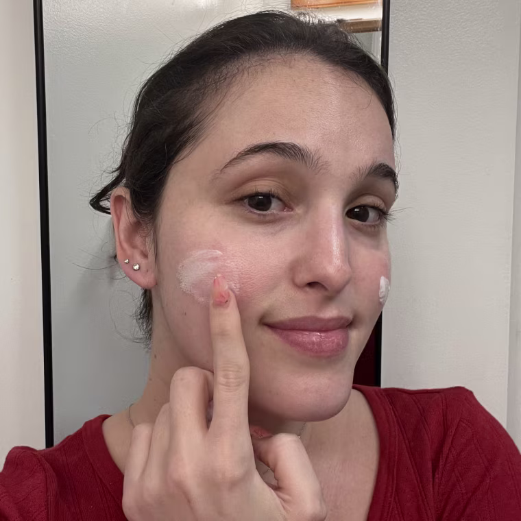Woman applying sunscreen to her cheek.