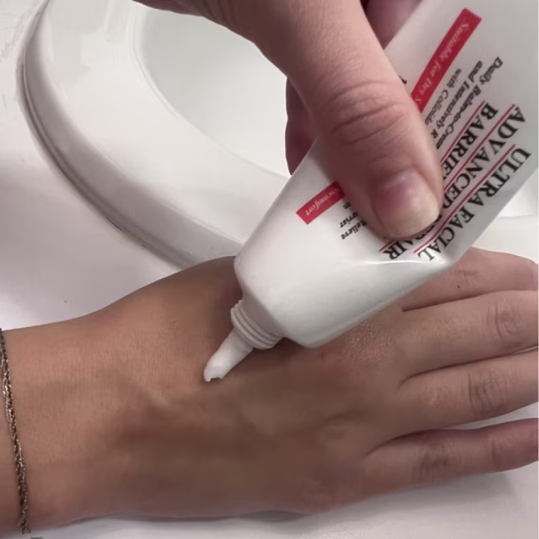 Woman dispensing cream on back of hand