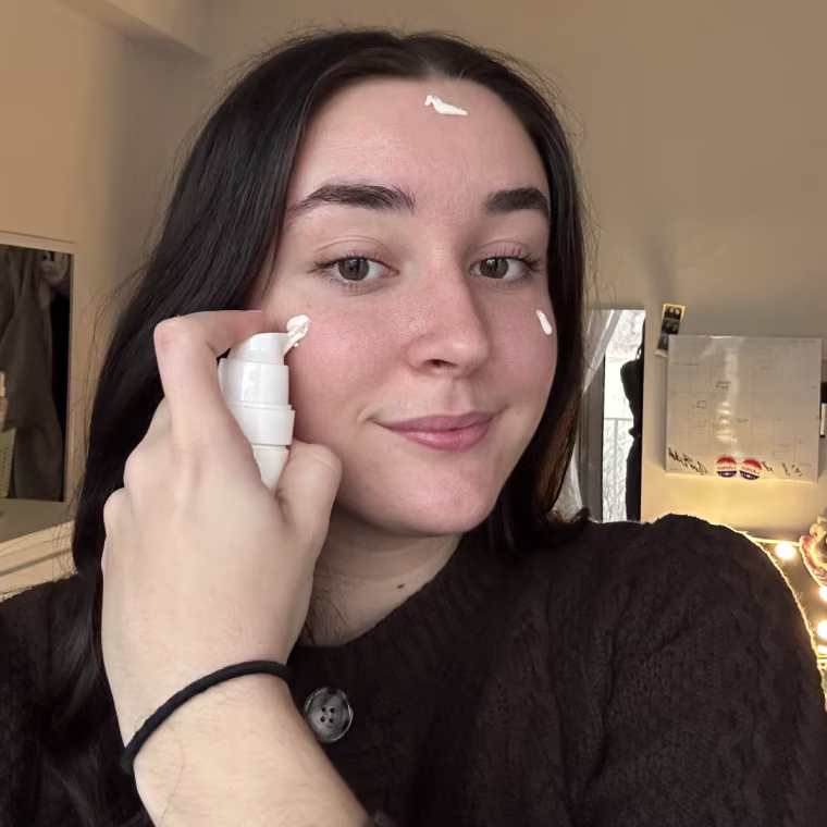 Woman applying sunscreen on face.