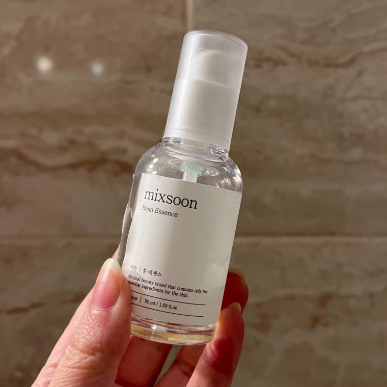 Woman holding serum bottle against a tile background