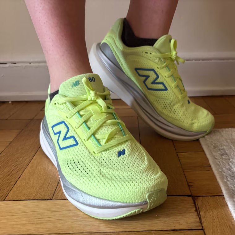 A person wearing a pair of yellow New Balance 1080v15 women’s running sneakers.