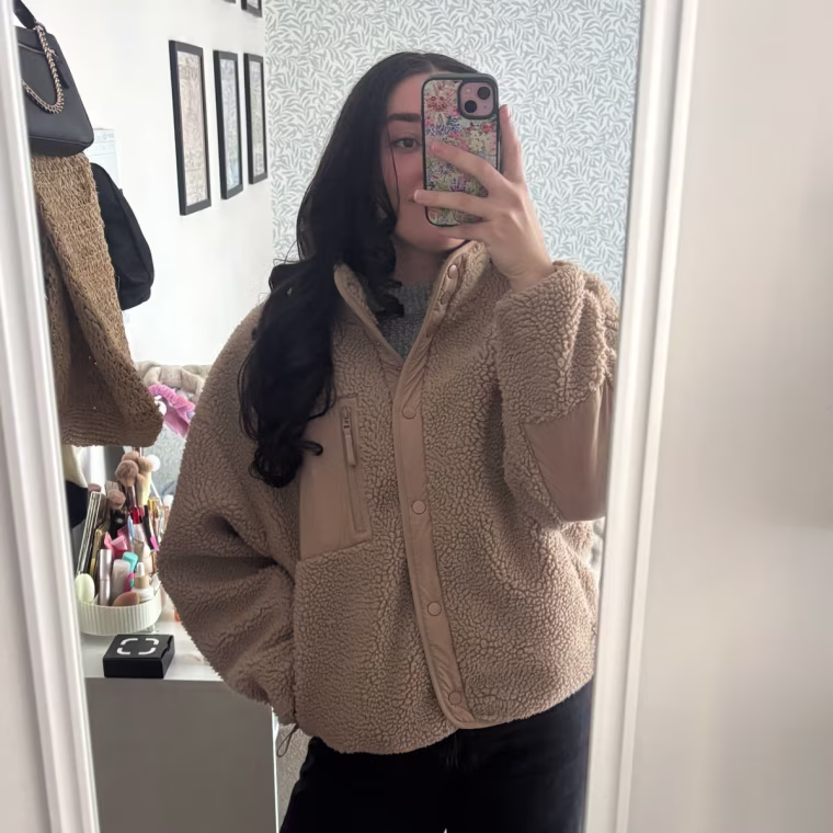 Photo of someone in a full-length mirror wearing a brown jacket, black pants and brown boots.