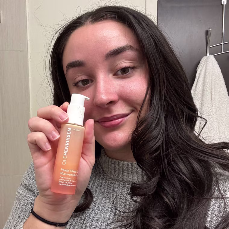 Person standing in bathroom applying a skin care product.