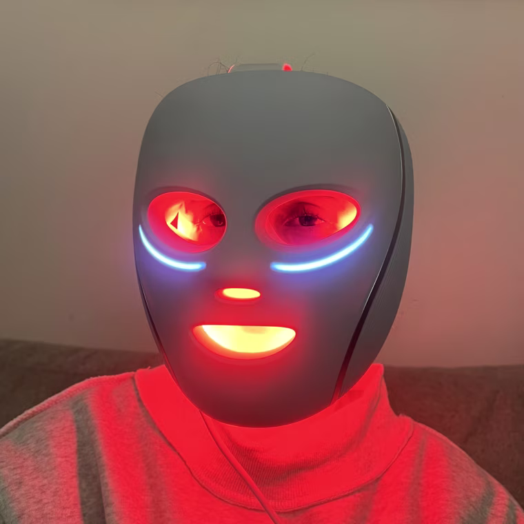 A close up of Godio wearing the Shark CryoGlow LED Face Mask. The lights emit a bright red glow from the eye, nose, and mouth cutouts.