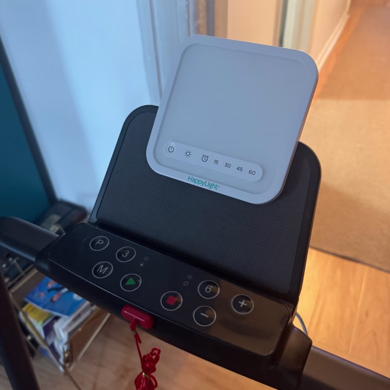 Photo of a VeriLux HappyLight Mini on the tablet stand of a walking pad.