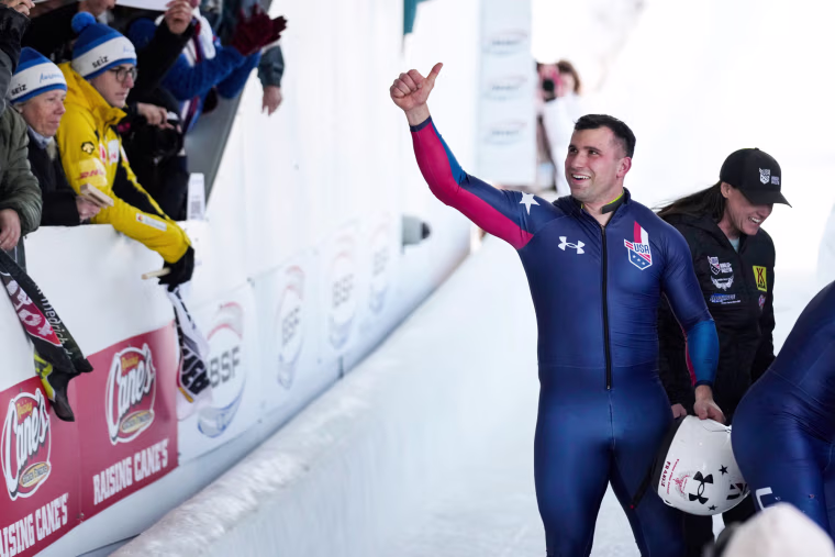 Frank Del Duca gives a thumbs up while passing by an audience outdoors in the snow