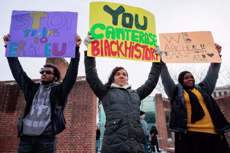 Three people hold signs next to one another