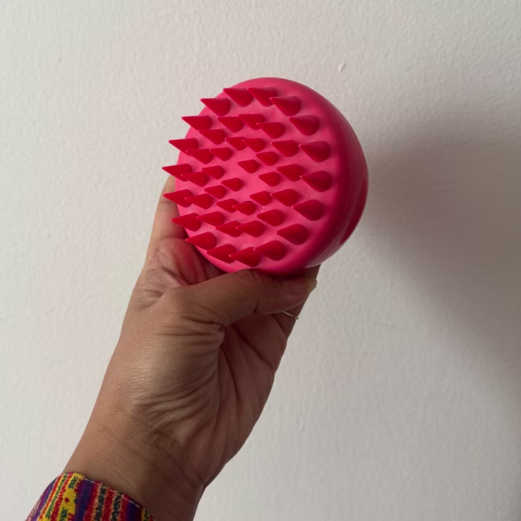 Woman holding pink scalp massager