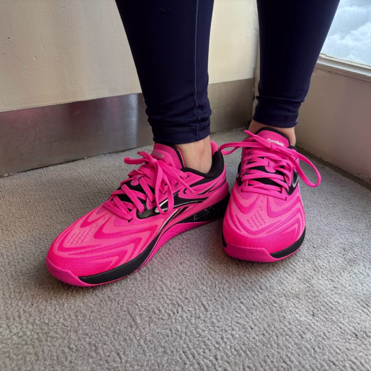 A close-up shot of someone wearing pink Reebok Nano X5 Edge training sneakers.