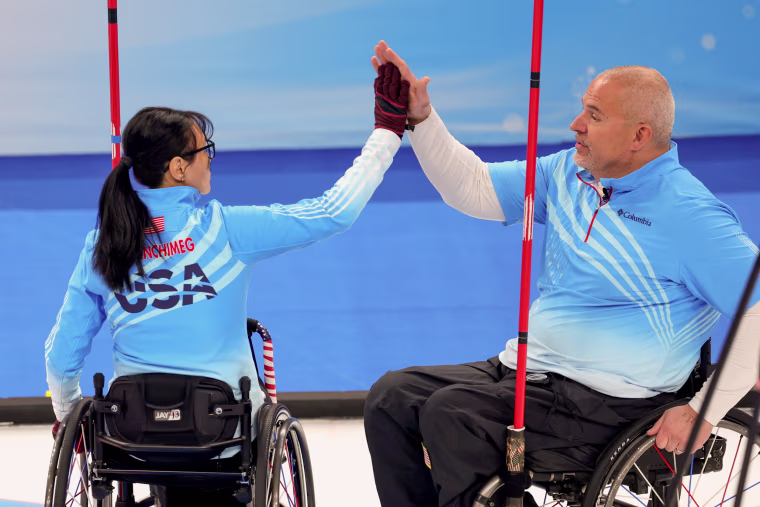 Batoyun Uranchimeg high fives Steve Emt of Team USA compete during wheelchair curling