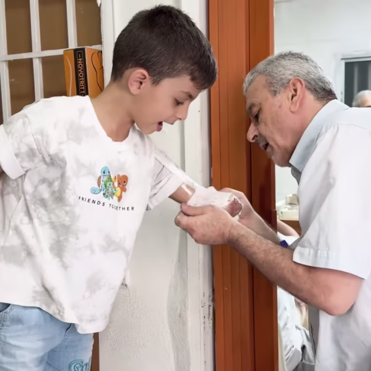 Omar's left arm, of which only half remains, is bandaged by a man