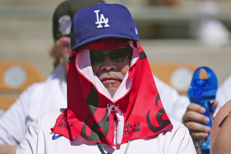 A Los Angeles Dodgers fan covers up from the hot sun during a spring training game on March 21, 2026, in Phoenix. 
