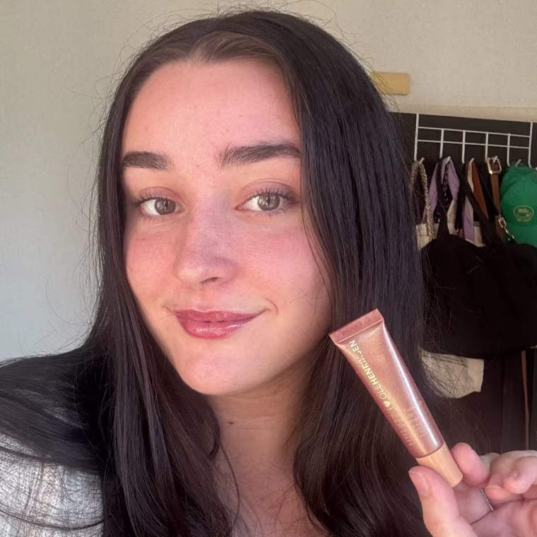 Woman showing lip treatment after applying it on lips