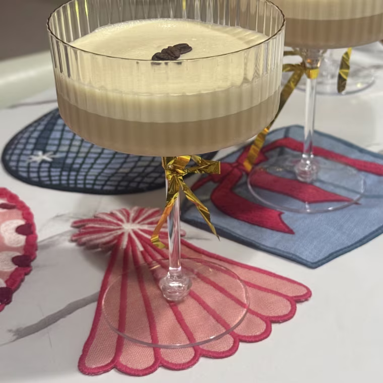 Cocktail glasses on a table with Piecework Puzzles Birthday Cocktail Napkins.