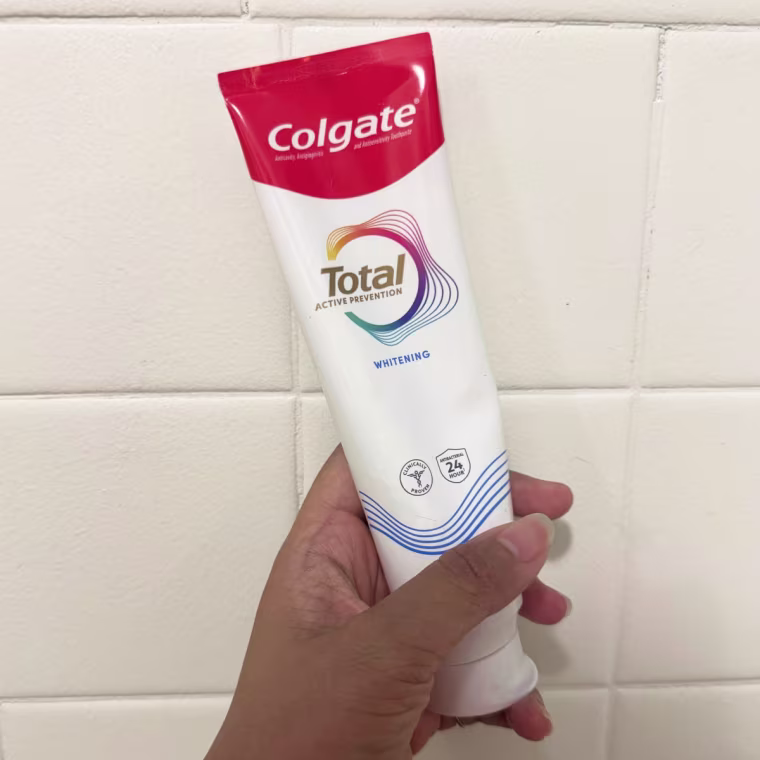 Hand holds a tube of Colgate Total Active Prevention Whitening Toothpaste
