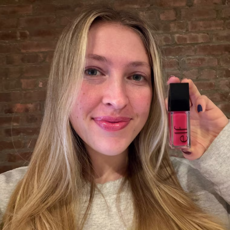 Woman holding up lip oil after applying to her lips