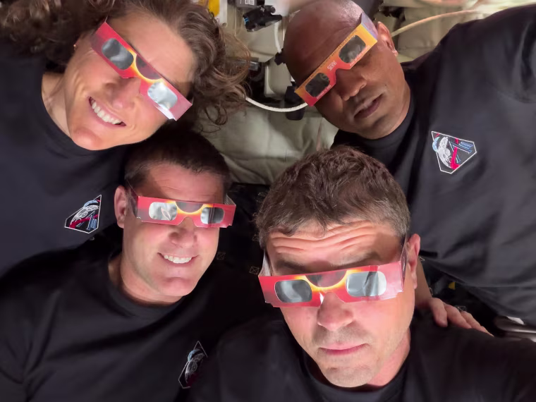 The Artemis II crew — clockwise from top left, mission specialist Christina Koch, pilot Victor Glover, commander Reid Wiseman and mission specialist Jeremy Hansen — use eclipse viewers during the solar eclipse they experienced during their lunar flyby.